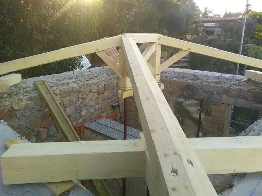 Charpente traditionnelle en bois à quatre pans en cours de réalisation.