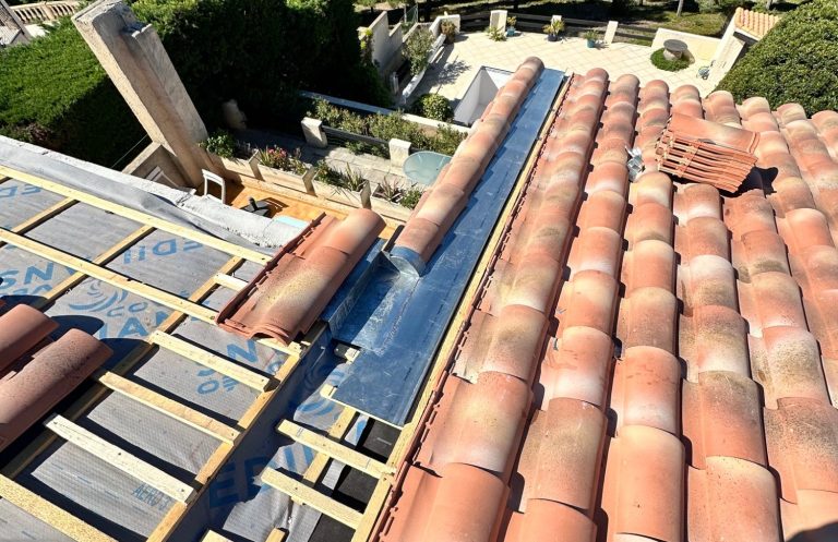 Réalisation d’un chéneau en zinc sur une toiture avec repose des tuiles pour assurer l’évacuation des eaux de pluie.