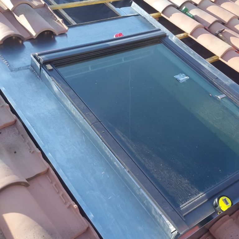 Artisan couvreur réalisant l’étanchéité d’un Velux avec un abergement en zinc sur une toiture à Marseille.