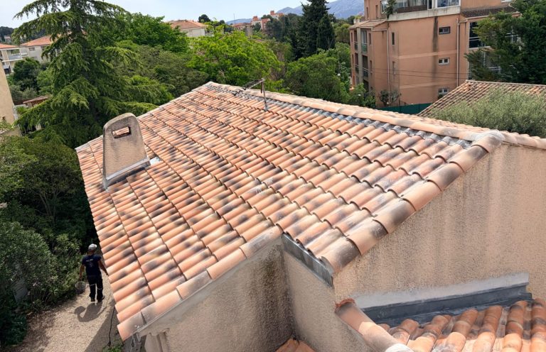 Toiture en tuiles avec cheminée et solin en zinc assurant l’étanchéité autour de la cheminée.