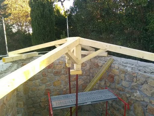 Charpente traditionnelle en bois à quatre pans en cours de réalisation.